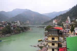 a view of a river with a bridge and buildings at Hotel V N Ganga in Rishīkesh