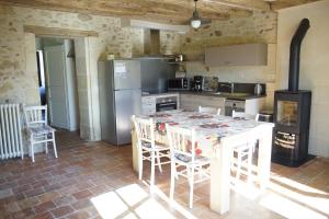 a kitchen with a table with chairs and a refrigerator at L'Abeille bleue in Cheillé