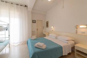 a white bedroom with a bed with towels on it at Hotel MIRO' in Cattolica