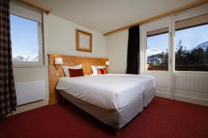 a bedroom with a large white bed and two windows at Crystal Hôtel in Courchevel