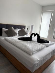 two black swans laying on a white bed at DAS LUDWIG - Haus HOCHLAND in Garmisch-Partenkirchen