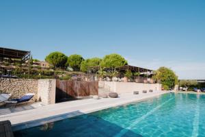 a swimming pool with two chairs next to a building at Coquillade Provence - Relais & Châteaux in Gargas