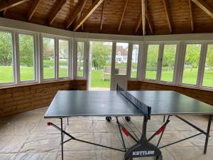 a ping pong table in a room with windows at Lakescape in Cirencester