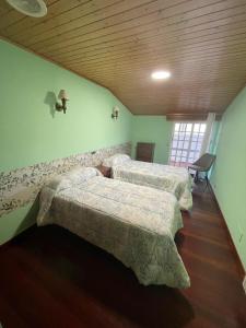a bedroom with two beds and a wooden ceiling at Hotel Victorino in Silleda