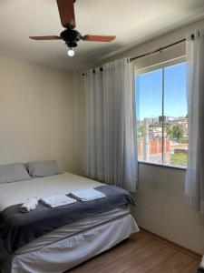 a bedroom with a bed with a ceiling fan and a window at Dois quartos centro in Ubá