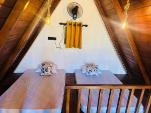 two beds in a attic room with yellow curtains at Sinharaja Brook Cabana in Deniyaya