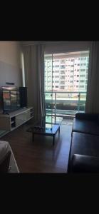 a living room with a glass coffee table and a large window at Dois quartos centro in Ubá