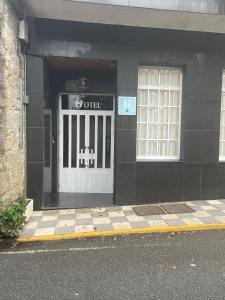 a black building with a door with a sign on it at Hotel Victorino in Silleda