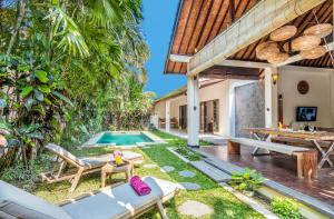 una imagen de un patio trasero con una piscina y una casa en Villa Can Barca, en Seminyak