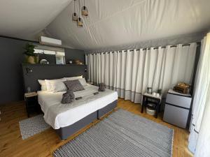 a bedroom with a large bed with white curtains at Jacil Riverside Accommodation in Hekpoort