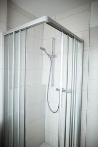 a shower in a white tiled bathroom at Hotel-Cafe Römer in Siegen