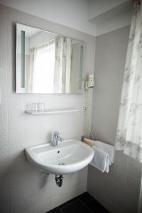 a white bathroom with a sink and a mirror at Hotel-Cafe Römer in Siegen +7 photos