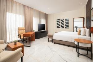 a hotel room with a bed and a living room at Aryaduta Palembang in Palembang