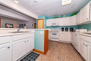 a kitchen with white cabinets and blue walls at Sunny Delight - KDH MP 7, Ocean View, 130 Yds to Beach, Pool, Hot Tub, Pets OK, Flex Stays in Kill Devil Hills