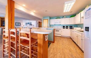 a kitchen with white cabinets and a island with bar stools at Sunny Delight - KDH MP 7, Ocean View, 130 Yds to Beach, Pool, Hot Tub, Pets OK, Flex Stays in Kill Devil Hills