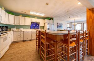 a kitchen with white cabinets and a bar with chairs at Sunny Delight - KDH MP 7, Ocean View, 130 Yds to Beach, Pool, Hot Tub, Pets OK, Flex Stays in Kill Devil Hills