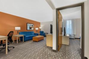 a hotel room with a blue couch and a tv at Pear Tree Inn Cape Girardeau West in Cape Girardeau