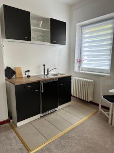 a kitchen with black cabinets and a sink and a window at Hotel Süden in Berlin
