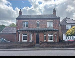 a brick house with a black door on a street at Coach house in Enderby +1 photo