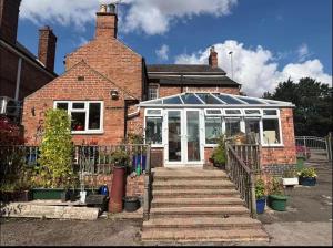 a brick house with a greenhouse on top of it at Coach house in Enderby