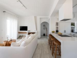 a white living room with a white couch and a kitchen at Lourdas White Villa in Kefallonia
