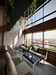 a living room with couches and tables and large windows at Ramada by Wyndham Oradea in Oradea