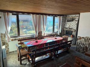 a dining room with a table and chairs and windows at къща Солунови in Dobrinishte