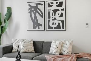 a living room with a gray couch and two framed pictures at Envitae Hotel 4BR Modern Sleek Apartment in Chicago