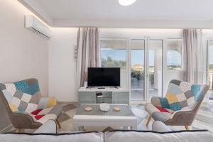 a living room with two chairs and a television at Villa Naisy in Tsilivi