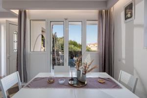 a white dining room with a table and a window at Villa Naisy in Tsilivi