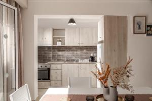 a kitchen with white cabinets and a table and chairs at Villa Dimi in Tsilivi