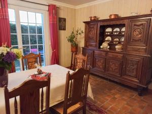 a dining room with a table and a large wooden cabinet at Charming Breton house in Hénansal in Hénansal