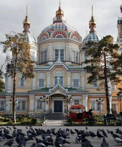 a large building with birds in front of it at Green Hill Hotel in Almaty