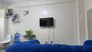 a living room with a blue couch and a tv at Emerald Tulivu Place in Ruaka