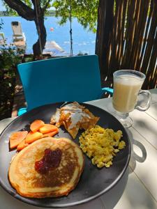 a plate of breakfast food on a table with a glass of milk at Hostal Estancia del Agua in Xul-Ha