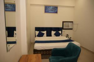 a bedroom with a bed and a chair and a mirror at Hotel Shyam Palace Near Kapurthala Mahanagar Lucknow in Lucknow