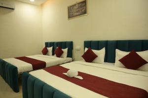 two beds in a hotel room with red and white at Hotel Shyam Palace Near Kapurthala Mahanagar Lucknow in Lucknow