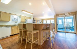 a kitchen with a bar with stools at Fly Boys - Nags Head MP 12.5, Oceanfront, Ocean View, Elevator, Pool Table, Hot Tub, YR Flex in Nags Head