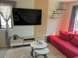 a living room with a red couch and a flat screen tv at Valley Escape in Cape Town