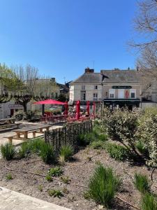 a patio with tables and red umbrellas in front of a building at La Maisonnette de Carreaux in Azay-le-Rideau