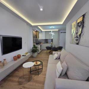 a living room with a white couch and a flat screen tv at Apartament Kwiatowy DeLux in Sanok
