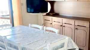 a dining room table with white chairs and a television at RM06 - Senigallia, trilocale fronte mare in Senigallia
