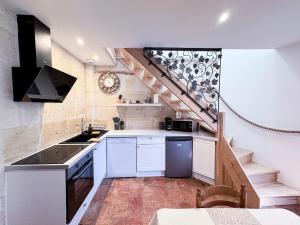 a kitchen with white cabinets and a spiral staircase at La Maisonnette de Carreaux in Azay-le-Rideau
