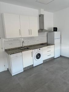 a white kitchen with a washing machine and a sink at El Merendero in Utrera