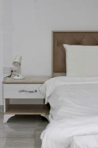 a white bed with a nightstand with a lamp on it at شاليه درة رأس الجنز Dorrat Ras Al Jinz Chalet in Junayz al Janūbī +81 photos