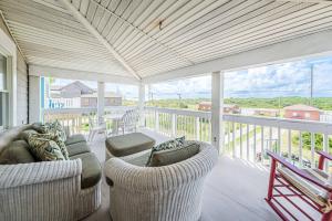 a porch with couches and chairs on a balcony at Dunes for Days - Nags Head MP 12.5, Oceanfront, Hot Tub, Rec Room, Pets OK, YR Flex in Nags Head