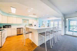 a kitchen with white cabinets and a counter with chairs at Dunes for Days - Nags Head MP 12.5, Oceanfront, Hot Tub, Rec Room, Pets OK, YR Flex in Nags Head
