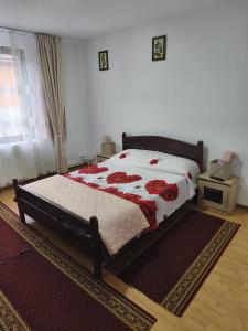 a bedroom with a bed with red flowers on it at Cabana Dany Colibița in Colibiţa