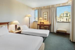 a hotel room with two beds and a window at Occidental Paris Levallois in Levallois-Perret
