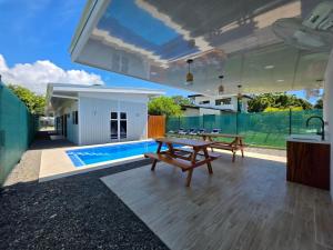 a patio with a table and benches and a swimming pool at Ocean Breeze at Life's a Beach in Uvita